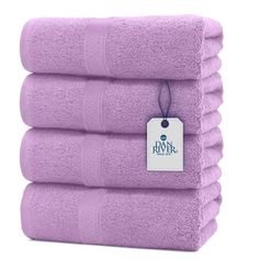 four purple towels stacked on top of each other with a tag hanging from the front