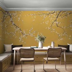 a dining room table with two chairs and a vase filled with flowers on the wall