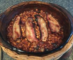 a bowl filled with beans and bacon on top of a table