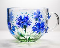 a glass coffee cup with blue flowers painted on the side and dots in the background