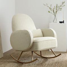 a white rocking chair sitting on top of a wooden floor