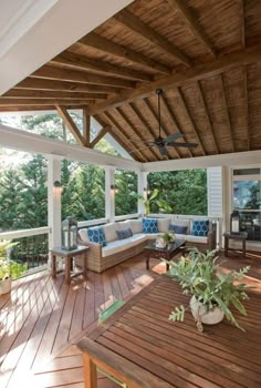 a covered porch with couches, tables and plants on the outside decking area