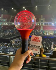 a person holding up a red and black object in front of an arena filled with people