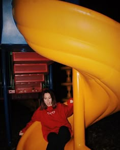 a woman sitting on top of a yellow slide