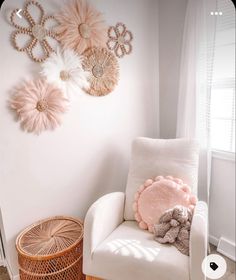 a white chair sitting in front of a window next to a wall hanging with decorative items on it