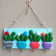 a wooden sign with cactus and hearts on it hanging from a rope against a wall