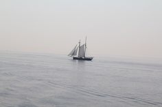 a sailboat sailing in the ocean on a foggy day