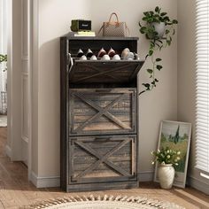 a wooden cabinet sitting in the corner of a room next to a potted plant