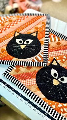 three black cats on orange and white quilted placemats, each with an individual's face