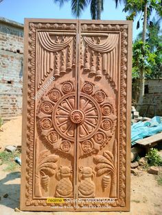 an intricately carved wooden door is shown in front of a brick wall and palm trees