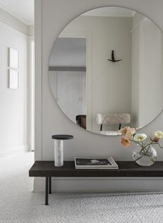 a vase with flowers on a table in front of a mirror