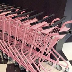 a row of pink shopping carts sitting on top of a black and white checkered floor