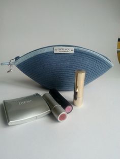 an assortment of cosmetics and makeup products on a white surface with a blue bag next to it