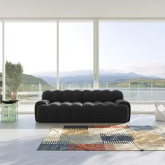 a modern living room with large windows overlooking the water and mountains is furnished with black leather sofas