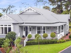 a grey house with white trim on the front porch and stairs leading up to it