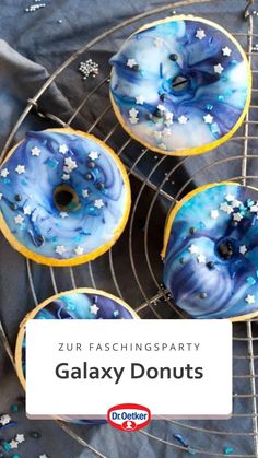 four doughnuts with blue icing and stars on them sitting on a cooling rack