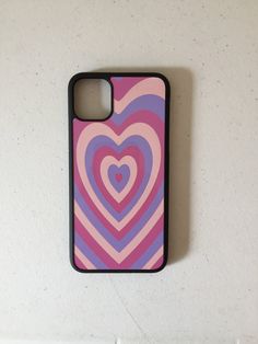 a pink and blue heart phone case on a white wall next to a black cellphone