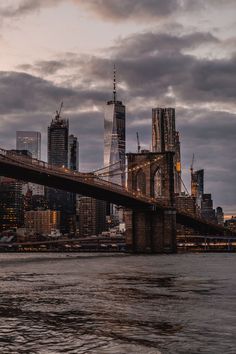 the city skyline is lit up at night with skyscrapers and bridge in foreground