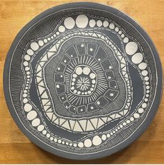 a black and white plate sitting on top of a wooden table