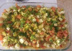 a glass dish filled with chopped vegetables on top of a counter next to a stove