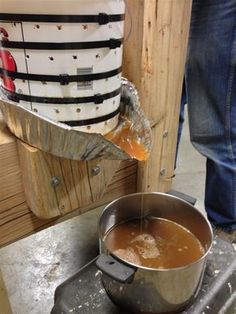 a person pouring liquid into a pot on top of a stove