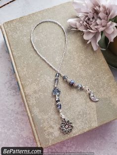 a book with a flower and beads on it next to a vase filled with flowers