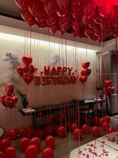 red balloons are hanging from the ceiling in front of a happy birthday sign with hearts