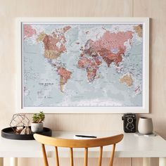 a map is hanging on the wall above a table with two chairs and a potted plant