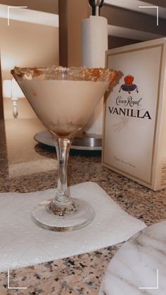 an empty martini glass sitting on top of a counter next to a bottle of vanilla