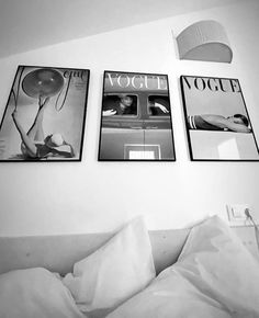 three black and white photographs hang on the wall above a bed with pillows, sheets, and lamps