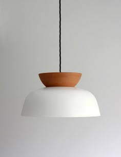 a white light hanging from a ceiling with a wooden bowl on it's end