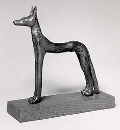 an old statue of a dog on a wooden block in front of a white background