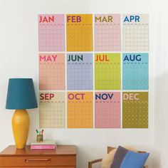 a colorful calendar is on the wall next to a chair and table with a lamp