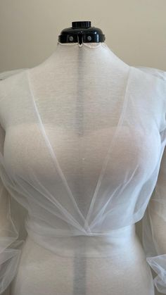 the back of a woman's white dress with sheer fabric and buttons on it