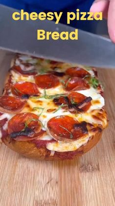 a person cutting up a pizza on top of a wooden table with the words cheesy pizza bread