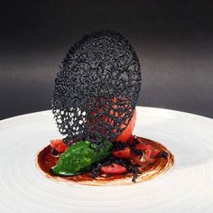 a white plate topped with food covered in sauce and garnished with black sprinkles