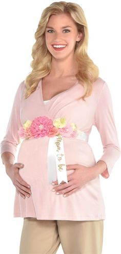 a pregnant woman wearing a pink top with flowers on the side and her belly in front