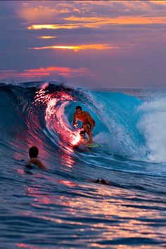 a man riding a wave on top of a surfboard in the ocean at sunset