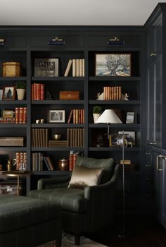 a living room filled with lots of bookshelves next to a couch and lamp