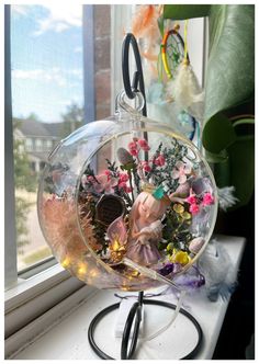 a glass ball with flowers in it sitting on a window sill