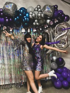 two women posing in front of balloons and streamers