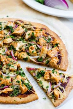 a pizza with chicken, onions and greens on it is cut into slices to be eaten