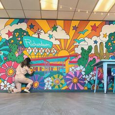 a woman kneeling down in front of a mural