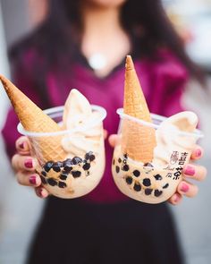 a woman holding two cups filled with ice cream