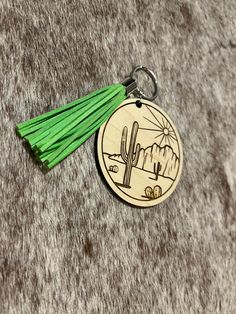 a wooden keychain with a green tassel hanging from it's side