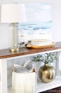 a shelf with a lamp, vase and other items on it next to a painting