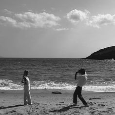 two people are on the beach taking pictures