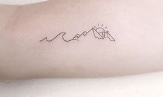 a small tattoo on the arm of a person with mountains and sun in the background