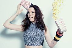 a woman holding two popcorn boxes in one hand and an empty box in the other