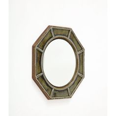 a small mirror on the wall with a hole in the middle that is shaped like a hexagonal object